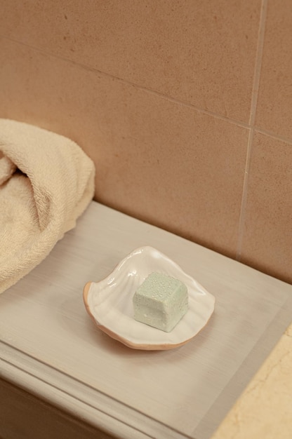 Natural bathroom decoration with white ceramic shell soap dish with a blue salt soap bar and towel