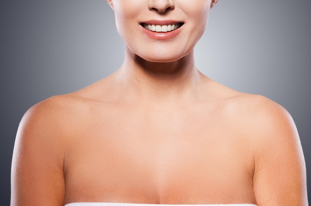 Natural beauty. Portrait of shirtless mature woman smiling while standing against grey background