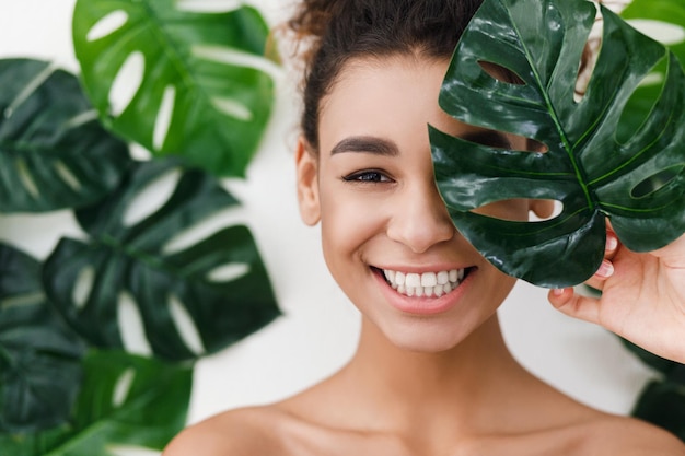 Natural beauty. Young woman with healthy skin over tropical leaves background