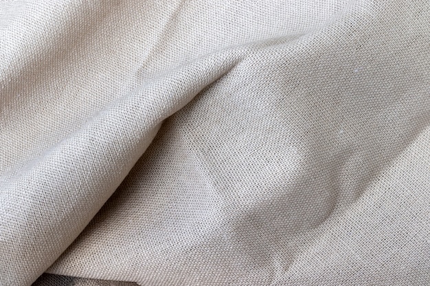 Текстура натуральной бежевой льняной ткани. Грубый фон мятой мешковины. Выборочный фокус. Крупным планом вид