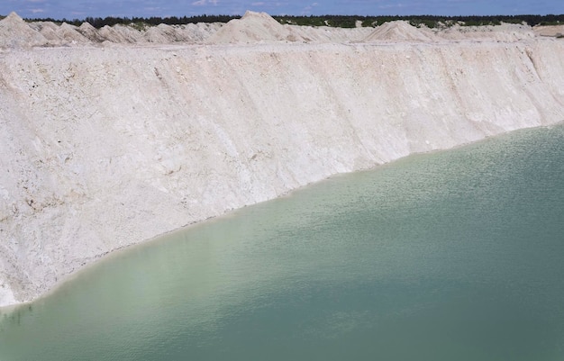 Естественная голубая вода в активном карьере мела с крутыми берегами и голубым небом