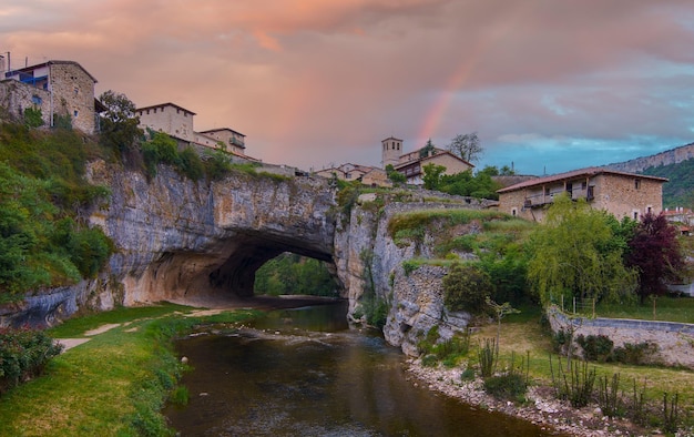 Natural bridge over the river with rainbow in the background