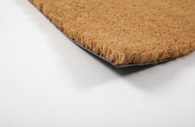 ナチュラル・ブラウン・ココナッツ・ファイバー・ドアマット (Natural Brown Coconut Fiber Doormat) はエントランスの外側に自然乾燥したカーペットと汚れを敷き白い背景のファイバーとベースの詳細クローズアップです