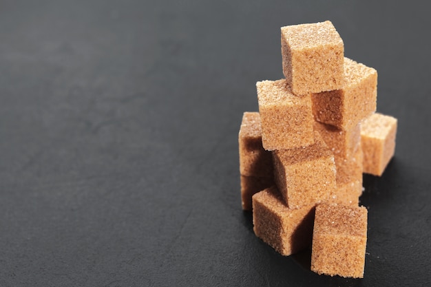 Natural brown sugar cubes on rough black 