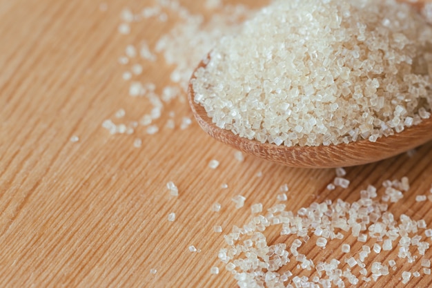 Natural brown sugar or no bleach sugar on wooden spoon in close up view macro concept.