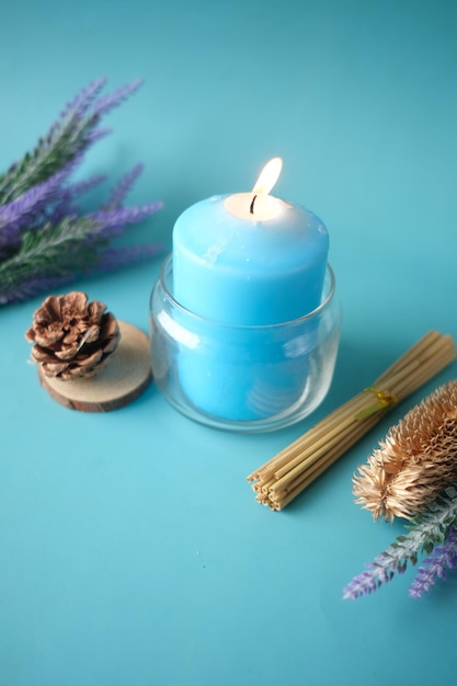 Natural candle in a glass jar and dried flowers on blue