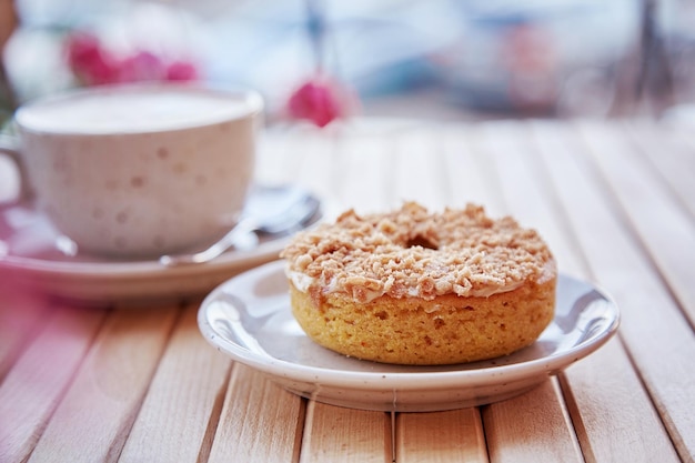 Natural caramel sweet doughnut with cappuccino on wooden table Aesthetic coffee time outside at the terrace