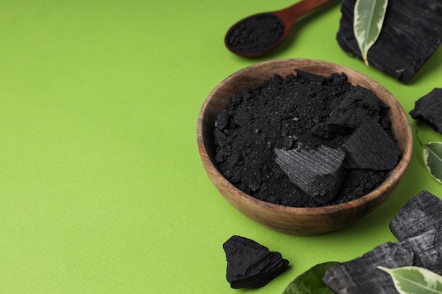 Natural charcoal and powdered charcoal on green background