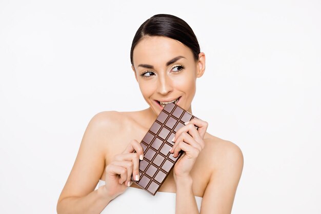 Natural chocolate Beautiful cheerful young woman holding a tile of black chocolate in hands on a white background