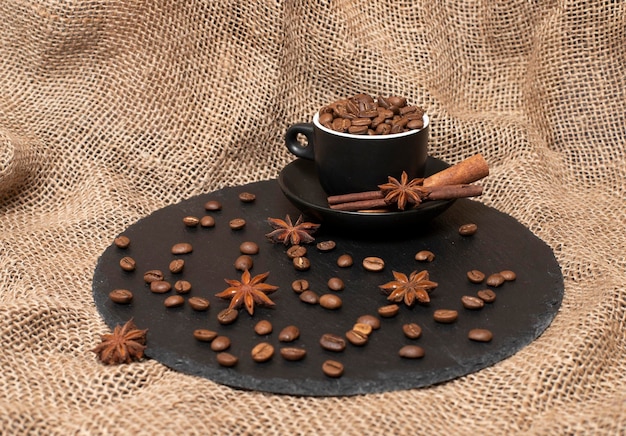 Natural coffee beans A cup of coffee with cinnamon and  anise on a background with sackcloth macro