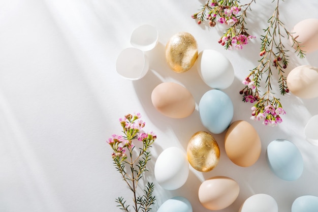 Натуральные цветные яйца и цветы с утренними лучами солнца. Стильные минималистичные композиции в пастельных тонах. Концепция пасхи.