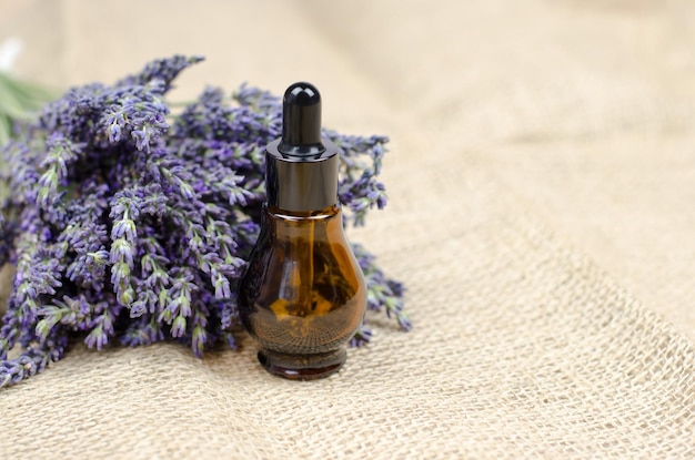 Photo natural cosmetic a bottle of lavender oil and a bouquet of fresh lavender on burlap caring for the skin natural essential oil of lavender