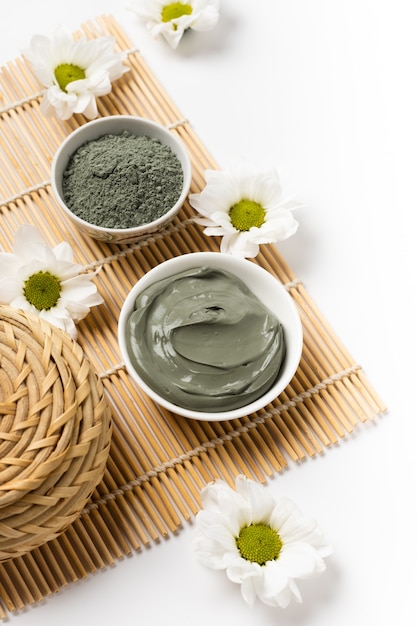 Natural cosmetic clay in bowls and with flowers on bamboo mat for spa salon