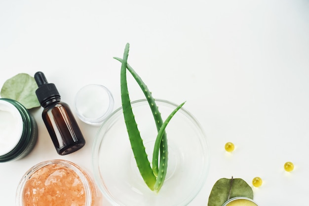 Contenitore cosmetico naturale della bottiglia di cura della pelle e foglia verde organica dell'aloe con vitamina c su fondo bianco. rimedio fatto in casa e concetto di prodotto di bellezza