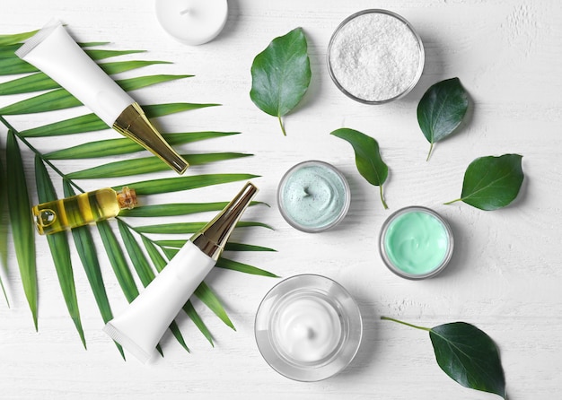 Natural cosmetics and leaves on wooden table