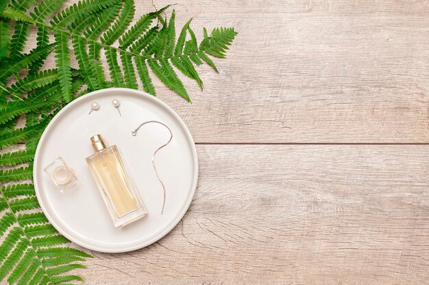 Natural cosmetics perfume essential serum in glass bottle jewelry accessoriesgreen fern branches