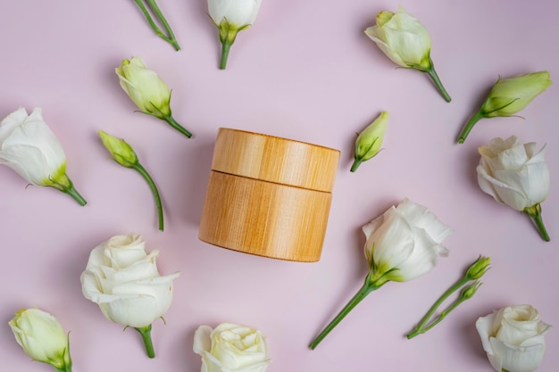 Natural cosmetics product with eustoma flowers and jar creme on\
a pink creative background top view and copy space flat lay