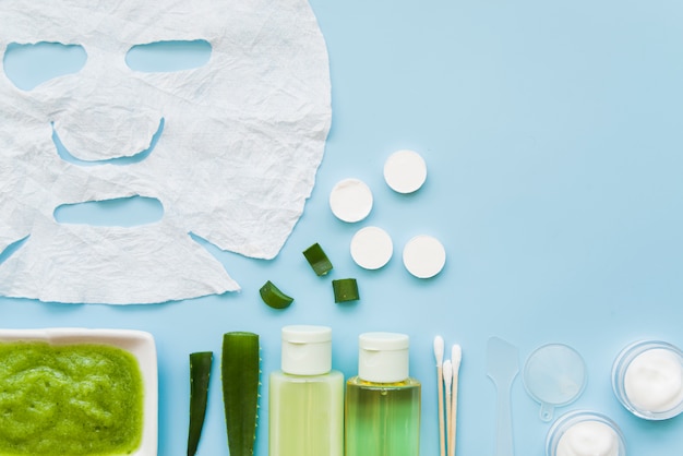 Natural cosmetics products with white face paper sheet on blue backdrop