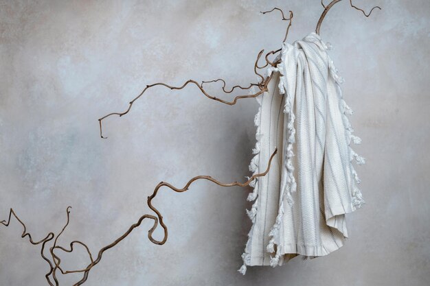 Фото Полотенце из натурального хлопка на ветвях ивы перед стеной минималистичная концепция ухода за ванной