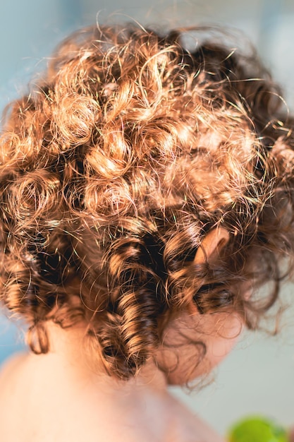 Photo natural curly hair little girl with light brown curls and golden reflections