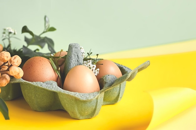 Фото Натуральные окрашенные стильные пасхальные яйца и весенние цветы на фоне желтой бумаги