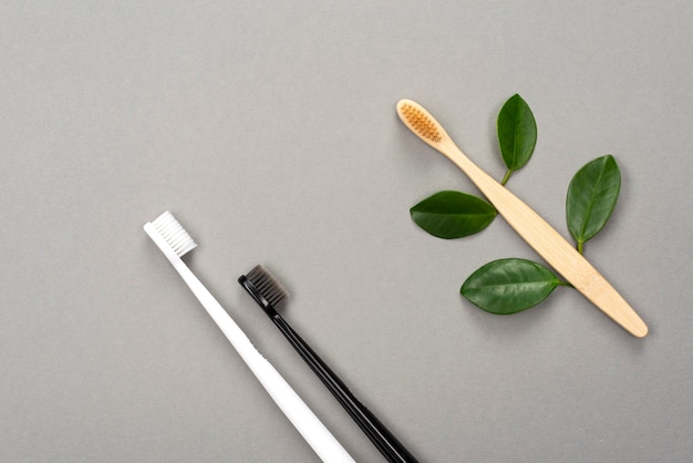 Natural eco friendly bamboo toothbrush and plastic toothbrush on gray surface
