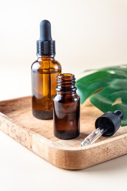 Natural essential oil, serum in brown glass bottles on a wooden traym. Alternative medicine, aromatic herbal beauty skin care product.