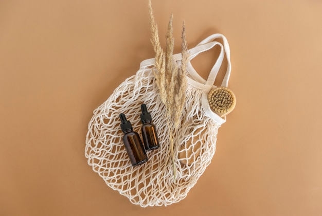 Photo natural essential oil or serum dropper bottles, natural facial brush lie on a mesh bag