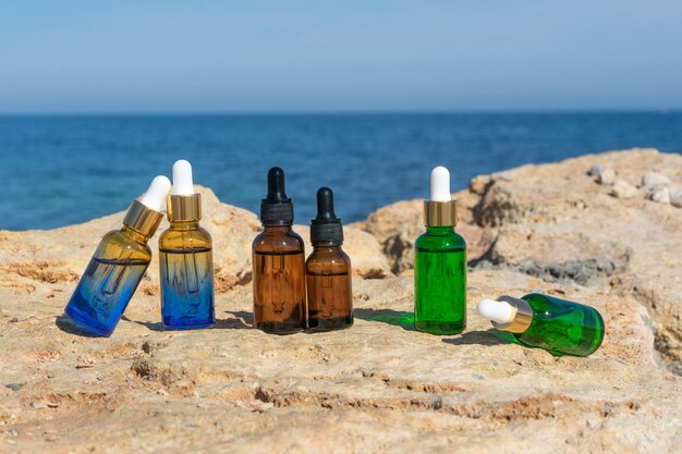 Natural essential oils or serum in dropper bottles standing on the stones at the seaside