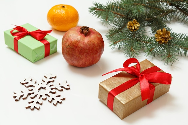 Natural fir tree branches with gift boxes and fruits on white background
