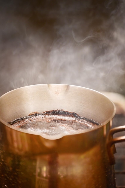 Photo natural freshly roasted coffee is prepared in a metal turk over a fire hot coffee with foam