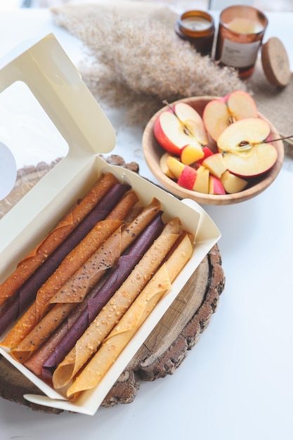 Natural fruit marshmallow in a white box on the background of a\
plate with apples and candles