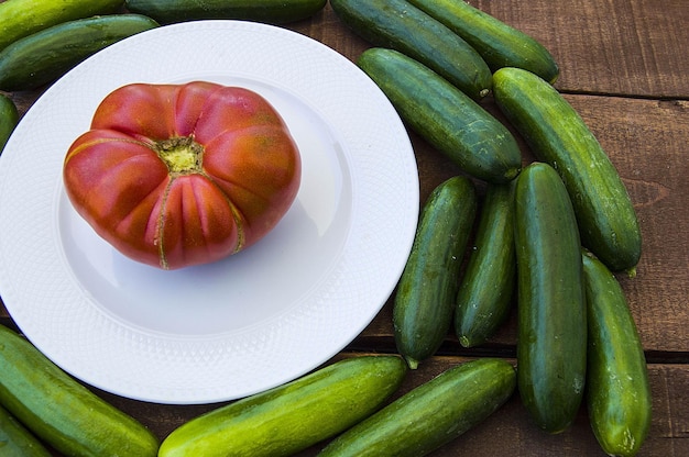 Natural garden cucumbers and natural large village tomatoes side by side on the wooden floor