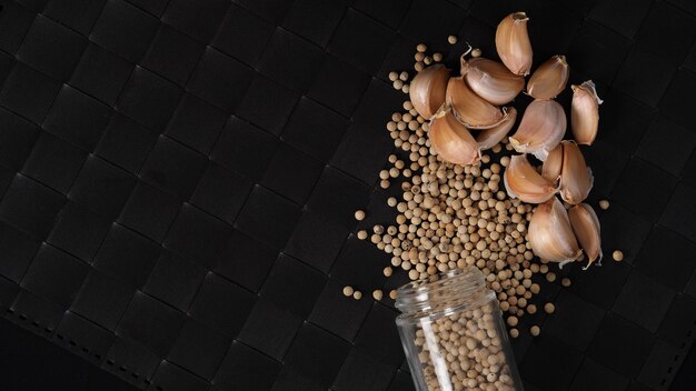 Natural Garlic and white peppercorn in glass bottle on plate mat black background in studio shot