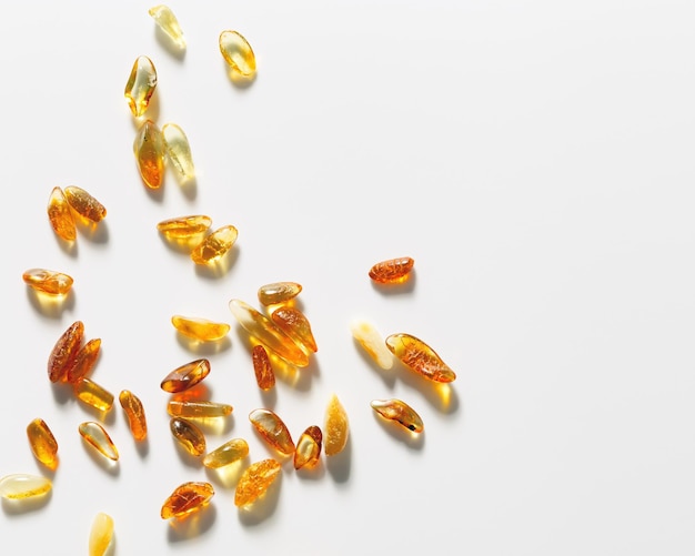 Natural gemstone amber texture background small stones at sunlight yellow orange color on white