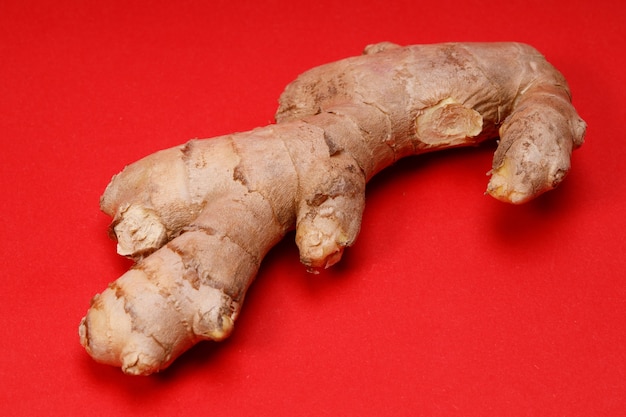 Photo natural ginger root on a red background