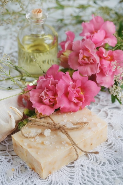 Natural handmade soap, aromatic oil and flowers on white wooden background. Spa concept.