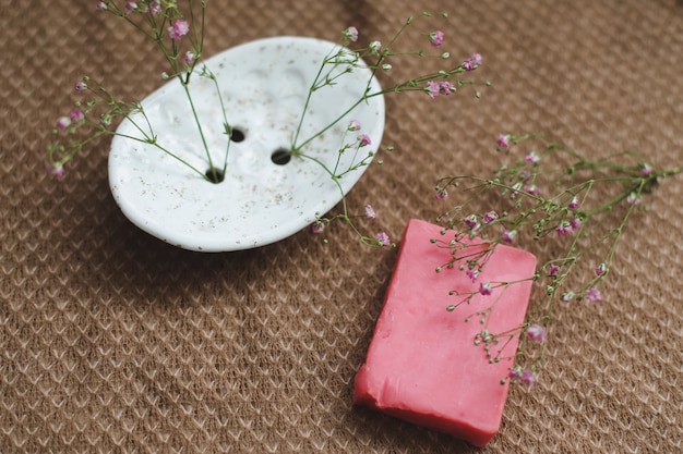 natural handmade soap bar with ceramic soap dish and flowers