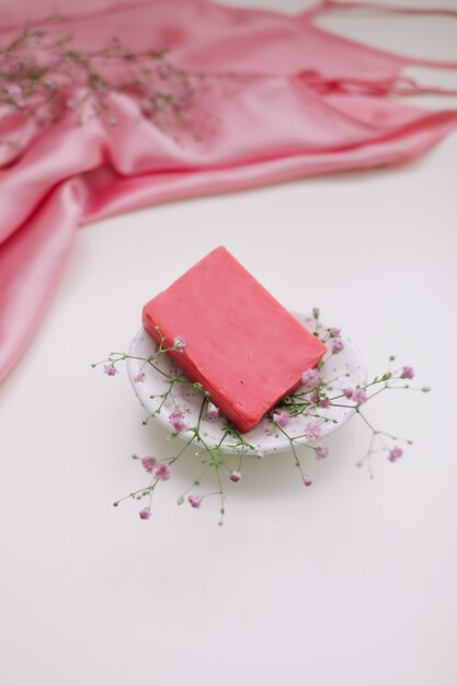 natural handmade soap bar with ceramic soap dish and flowers