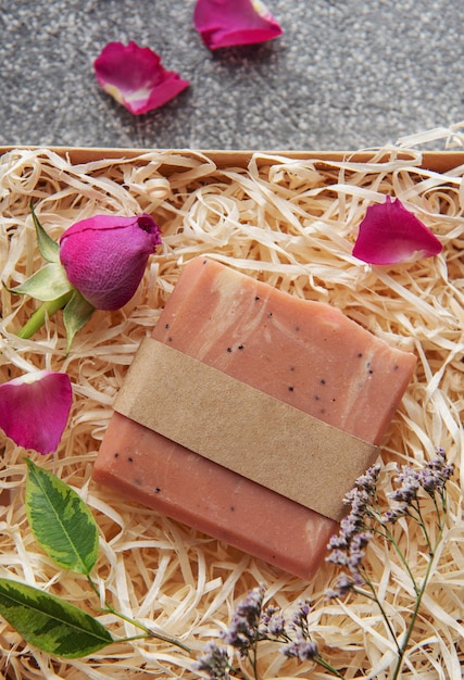 Photo natural handmade soap with rose petals on straw background