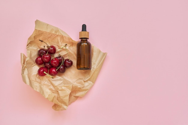 Natural healthy organic cosmetics, fruits, cherries, bottle with cosmetic product on pink background. Cosmetology, treatment, skincare, therapy