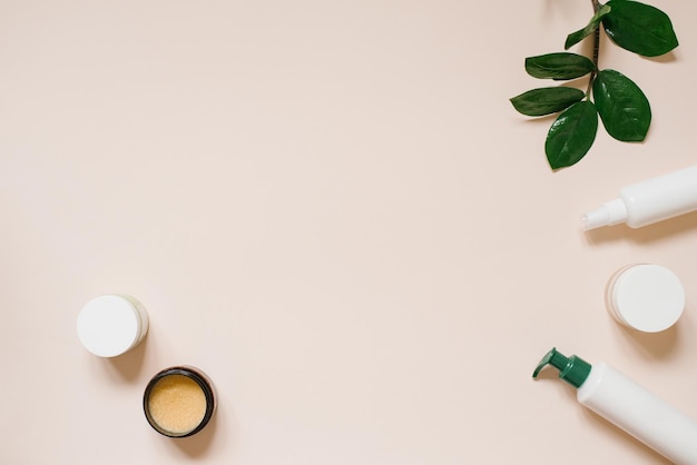 Photo natural herbal creams in bottles and jars with green leaves on a light beige background with copy space the concept of a natural organic cosmetic product flat position top view