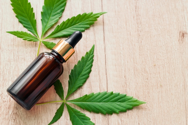 natural herbal hemp essential oil in a glass bottle and marijuana green leaves