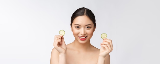 Натуральная домашняя свежая огуречная прокладка для глаз маски для лица Азиатская женщина, держащая огуречные прокладки и улыбка расслабиться с натуральной домашней