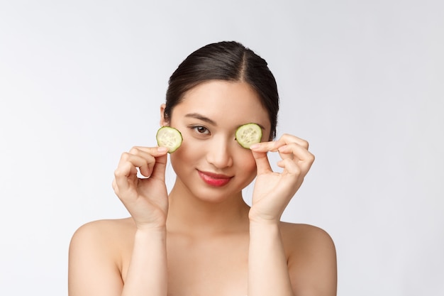 Natural homemade fresh cucumber facial eye pads facial masks Asian woman holding cucumber pads and smile relax with natural homemade