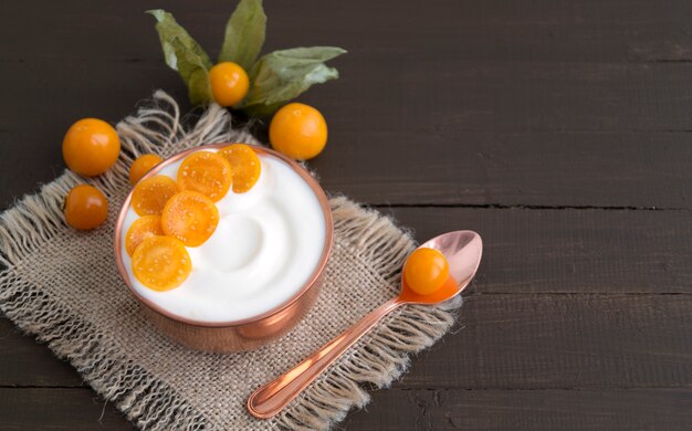 Foto yogurt naturale fatto in casa con macinata di ciliegia su un tavolo di legno.