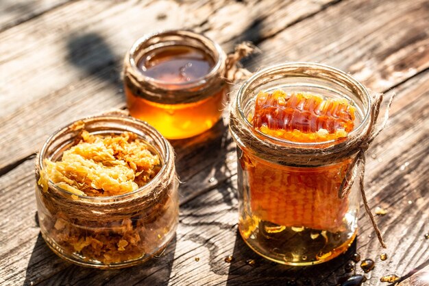 Natural honey comb and a glass jar on wooden table Honey background Sweet honey Long banner format space for text