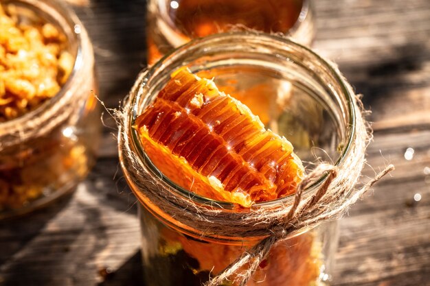 Natural honey comb and a glass jar on wooden table