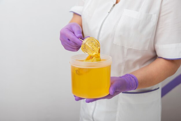 Natural honey sugar paste shugaring closeup women beautician holds jar wax of paste for sugar depila...