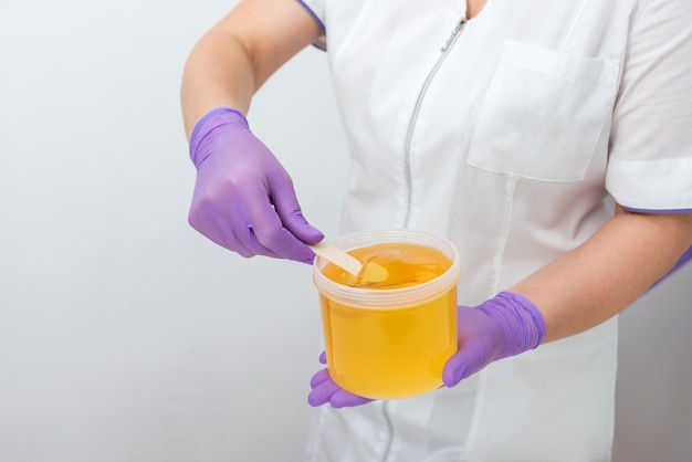 Natural honey sugar paste shugaring closeup women beautician holds jar wax of paste for sugar depila...